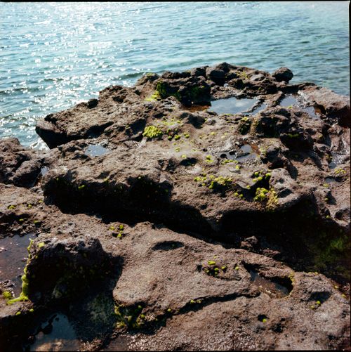 Free Rocky coastal formations with water in Quang Ngai, Vietnam, under bright sunlight. Stock Photo