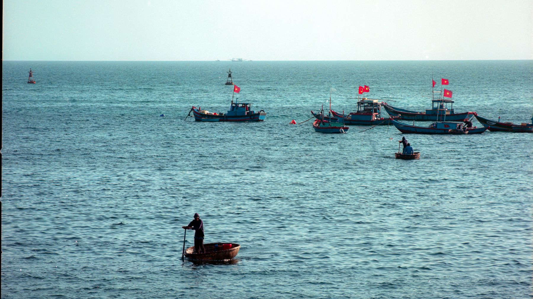 Fishermen navigate traditional boats on the tranquil sea in Quang Ngai, Vietnam.