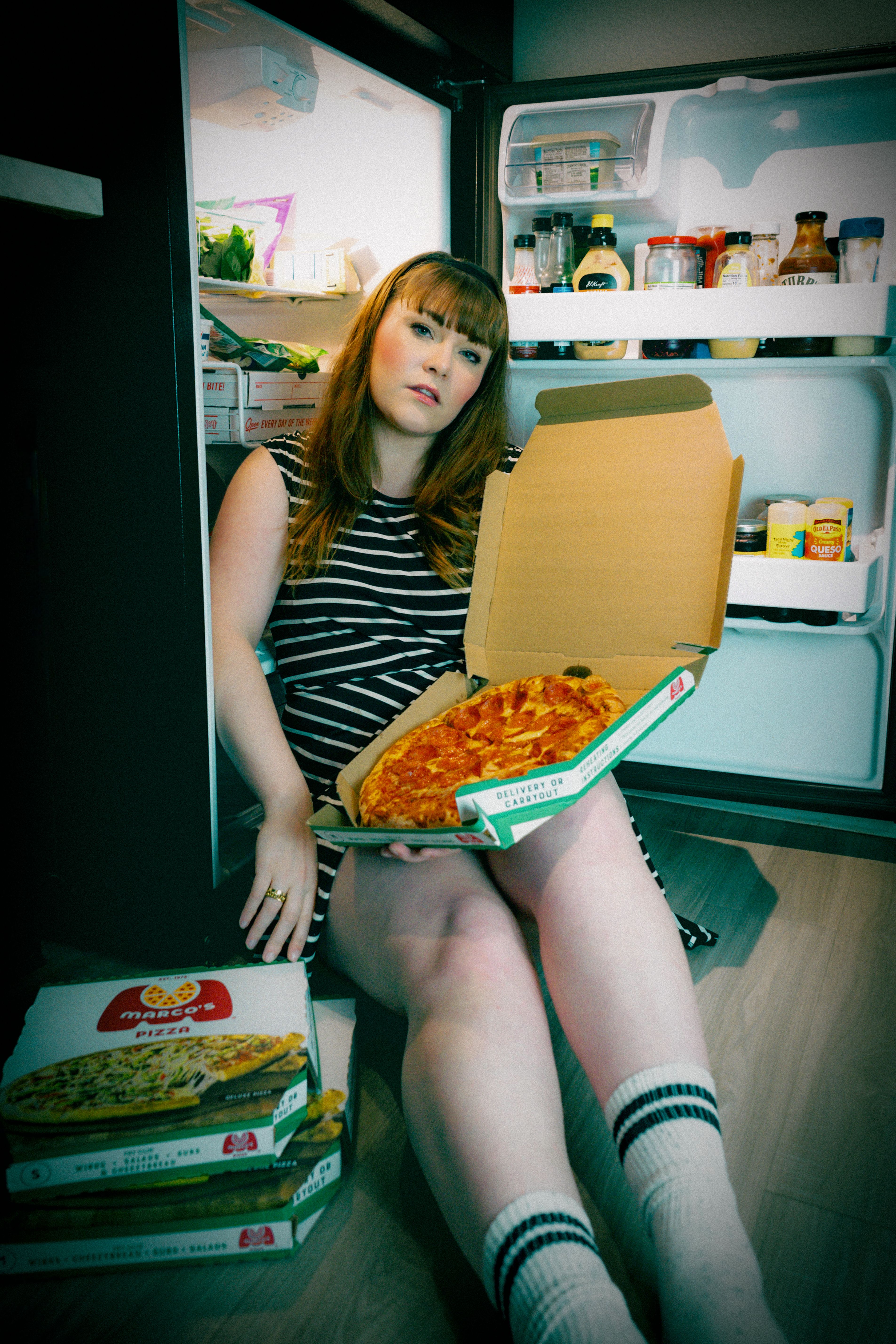 Open refrigerator showing leftover pizza stored on a shelf inside