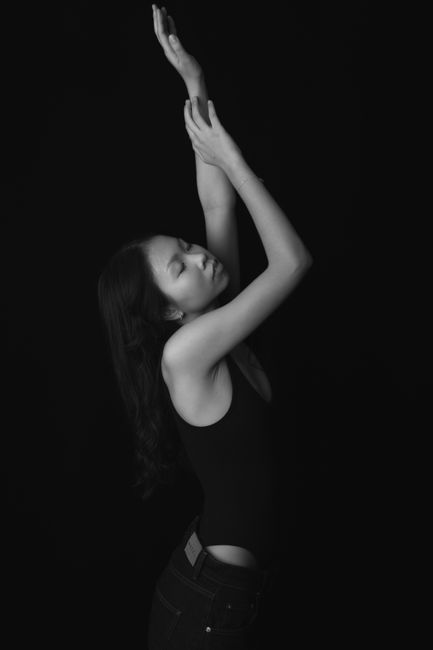 Artistic black and white portrait of a woman in a graceful dance pose.