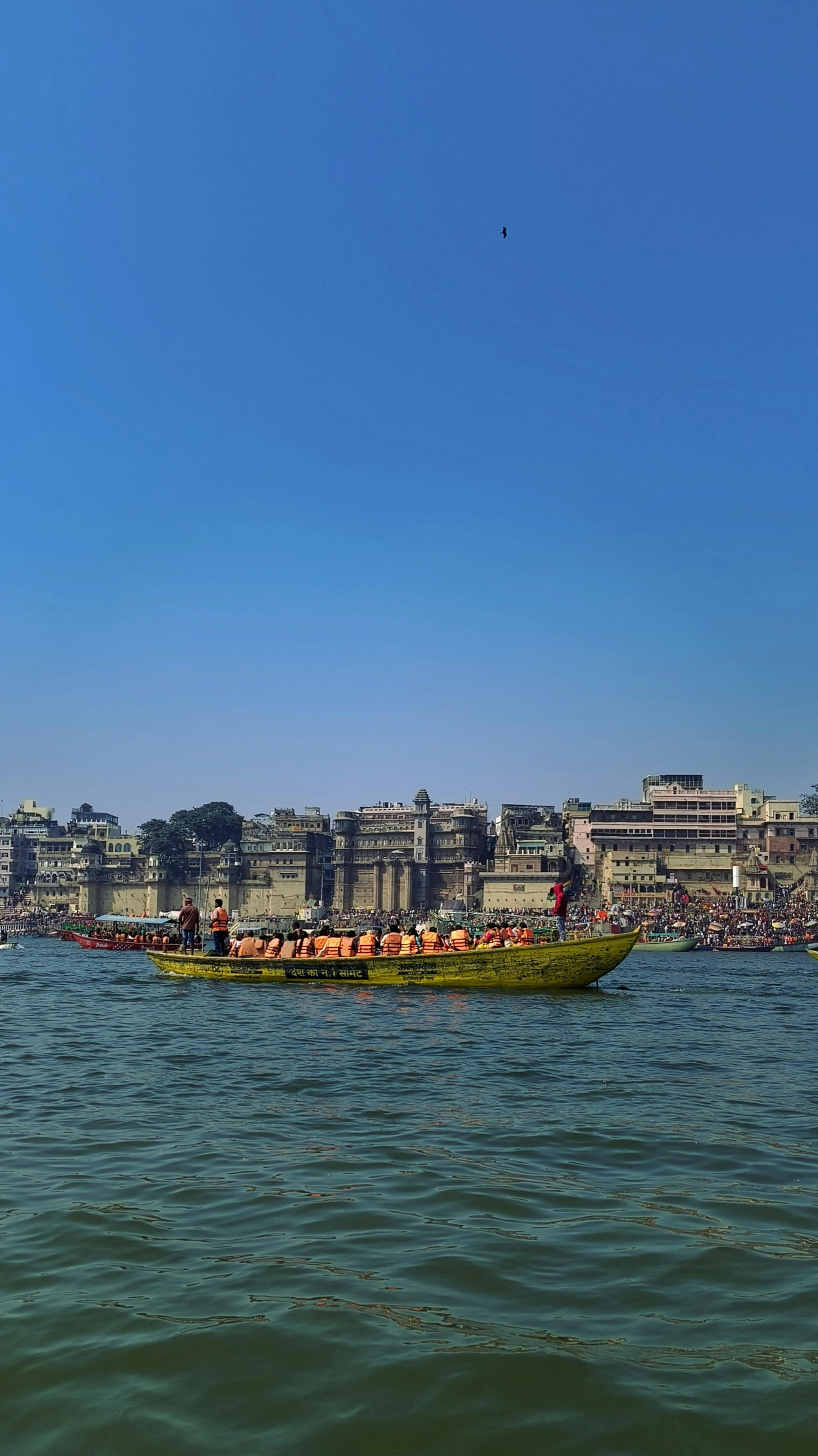 People on a boat on the Ganges River with Varanasi ghats in the background.