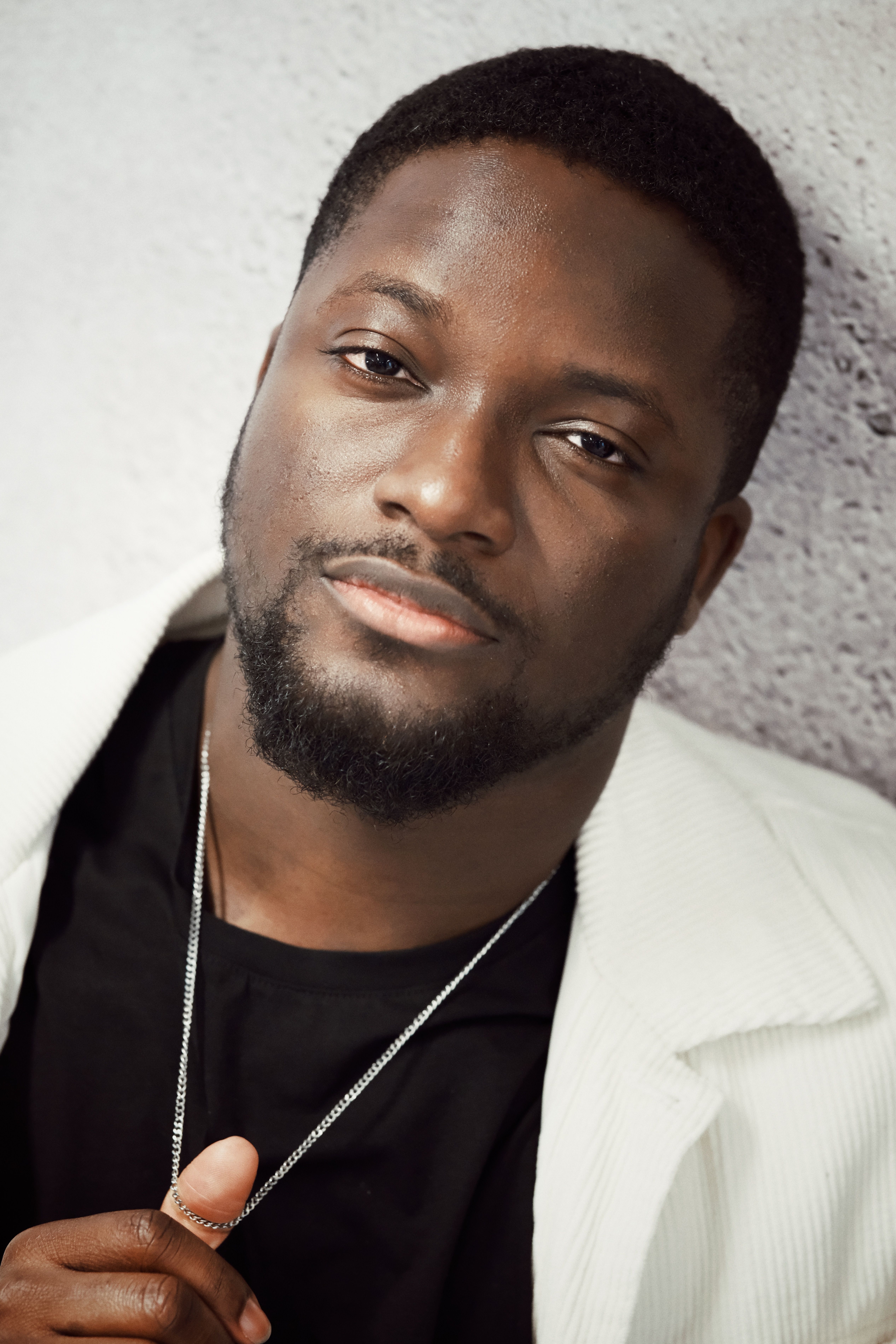 A detailed close-up shot of a confident man in a white jacket, expressing calmness.