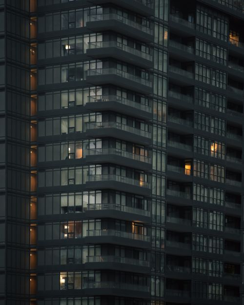 Free A dark, moody image of a Toronto high-rise building with illuminated windows at dusk. Stock Photo