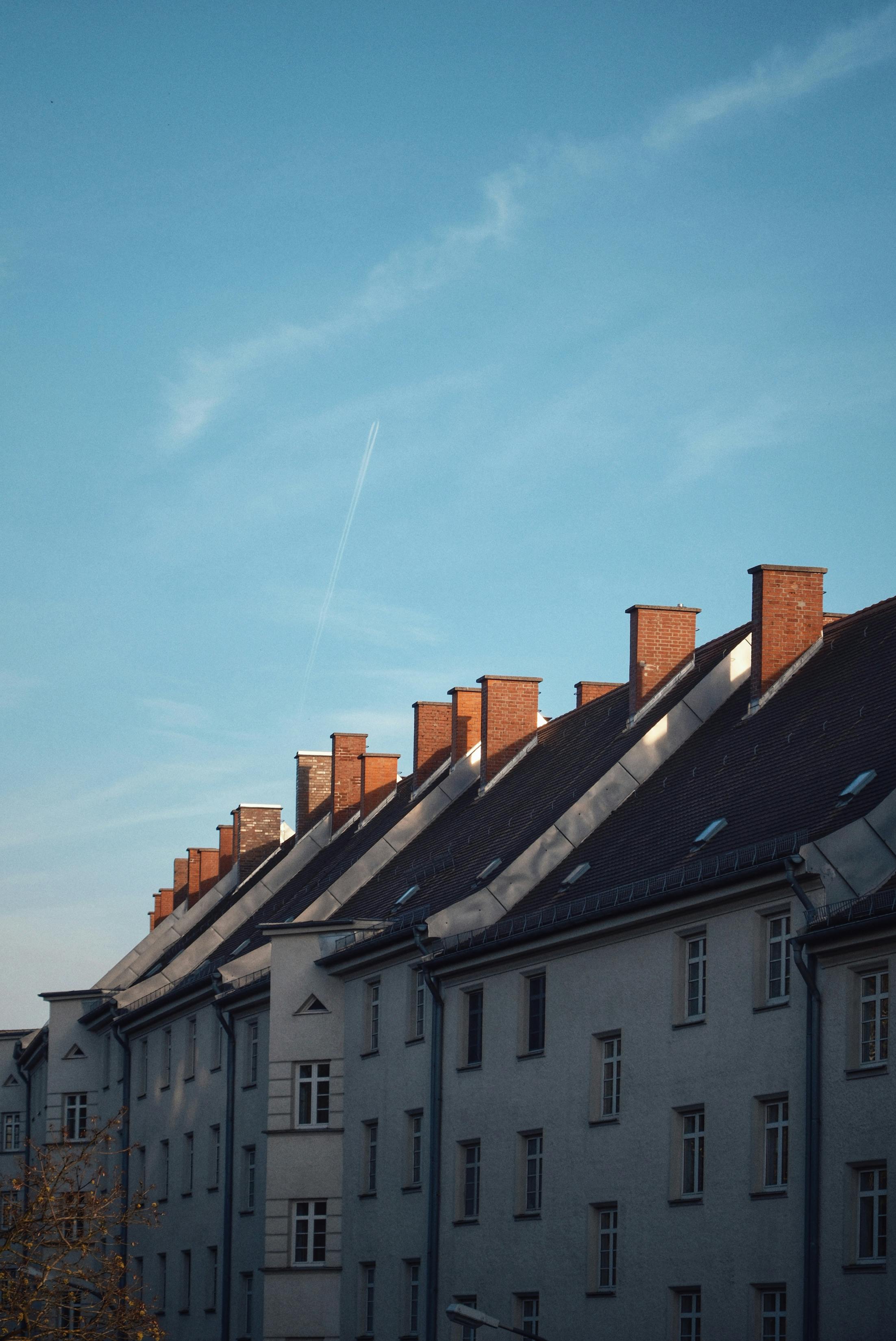 Reihe von Wohngebäuden mit Schornsteinen unter einem klaren blauen Himmel. Städtische Architektur.