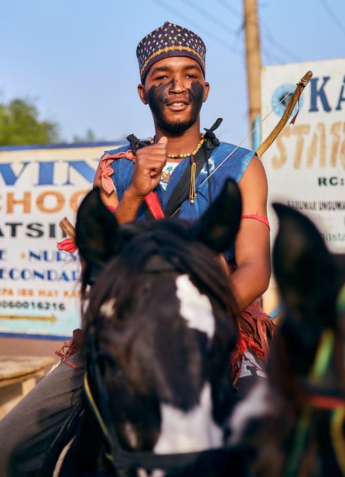 Free An African man in traditional attire rides a horse during a cultural festival, showcasing rich traditions. Stock Photo