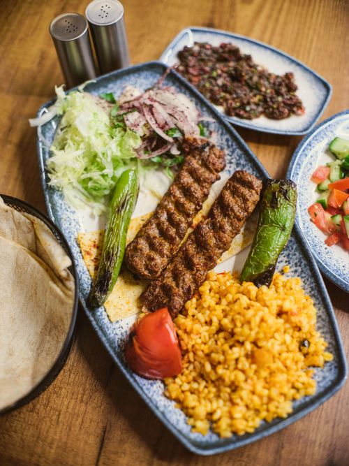 Free Mouth-watering Turkish kebab with bulgur pilaf, grilled vegetables, salad, and flatbread served on a wooden table. Stock Photo