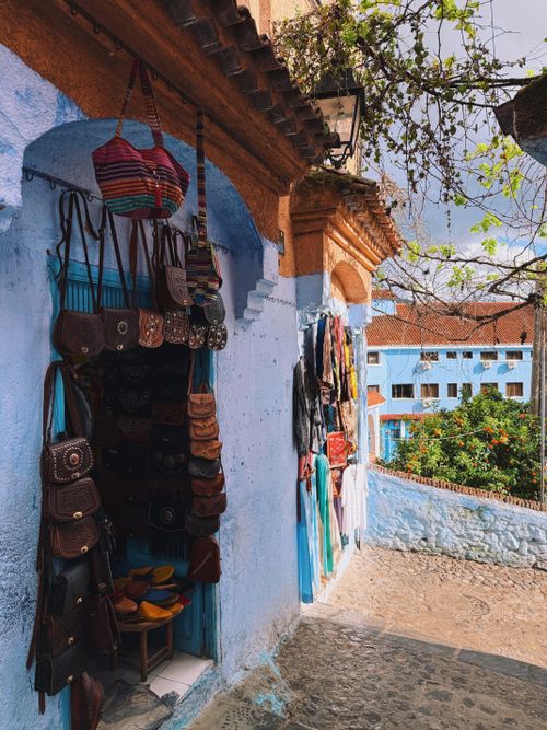 Free Vibrant street market in Chefchaouen, Morocco showcasing traditional bags and textiles. Stock Photo