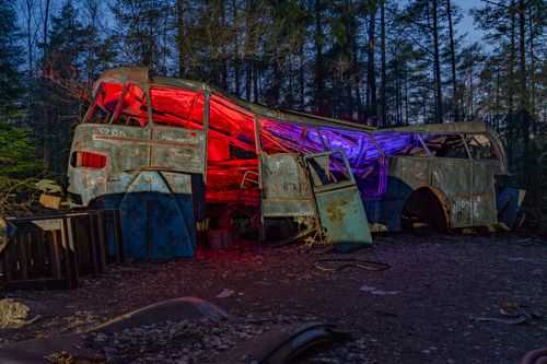 Free Rusty bus with colorful neon lights in a dark forest setting. Surreal atmosphere. Stock Photo