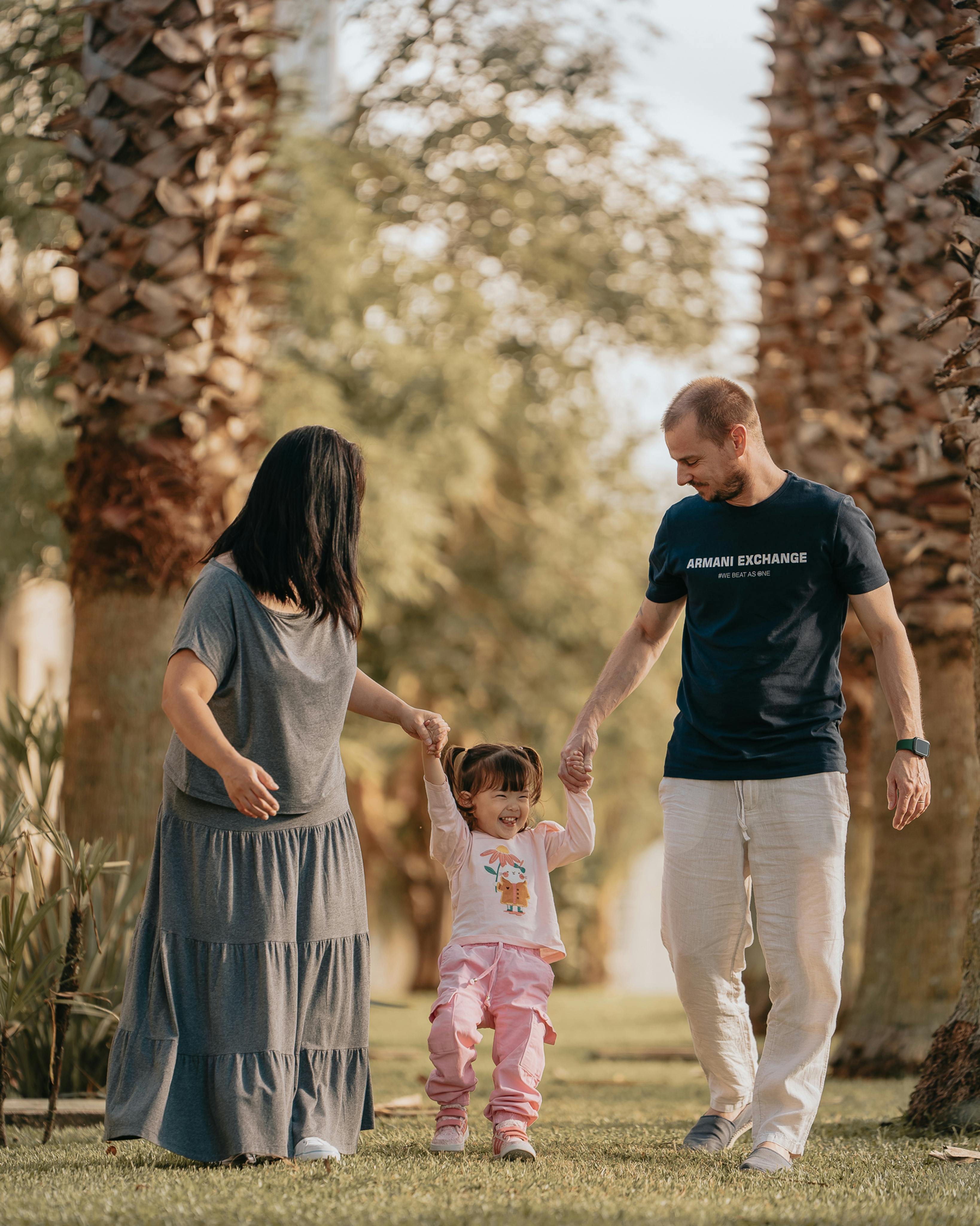 Free A joyful family walking together in a sunny Curitiba park, embodying love and happiness. Stock Photo