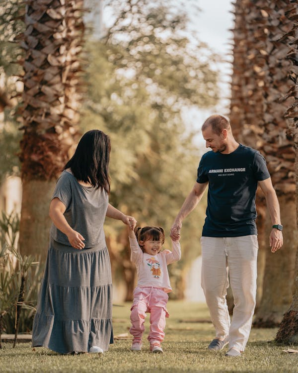 Free A joyful family walking together in a sunny Curitiba park, embodying love and happiness. Stock Photo