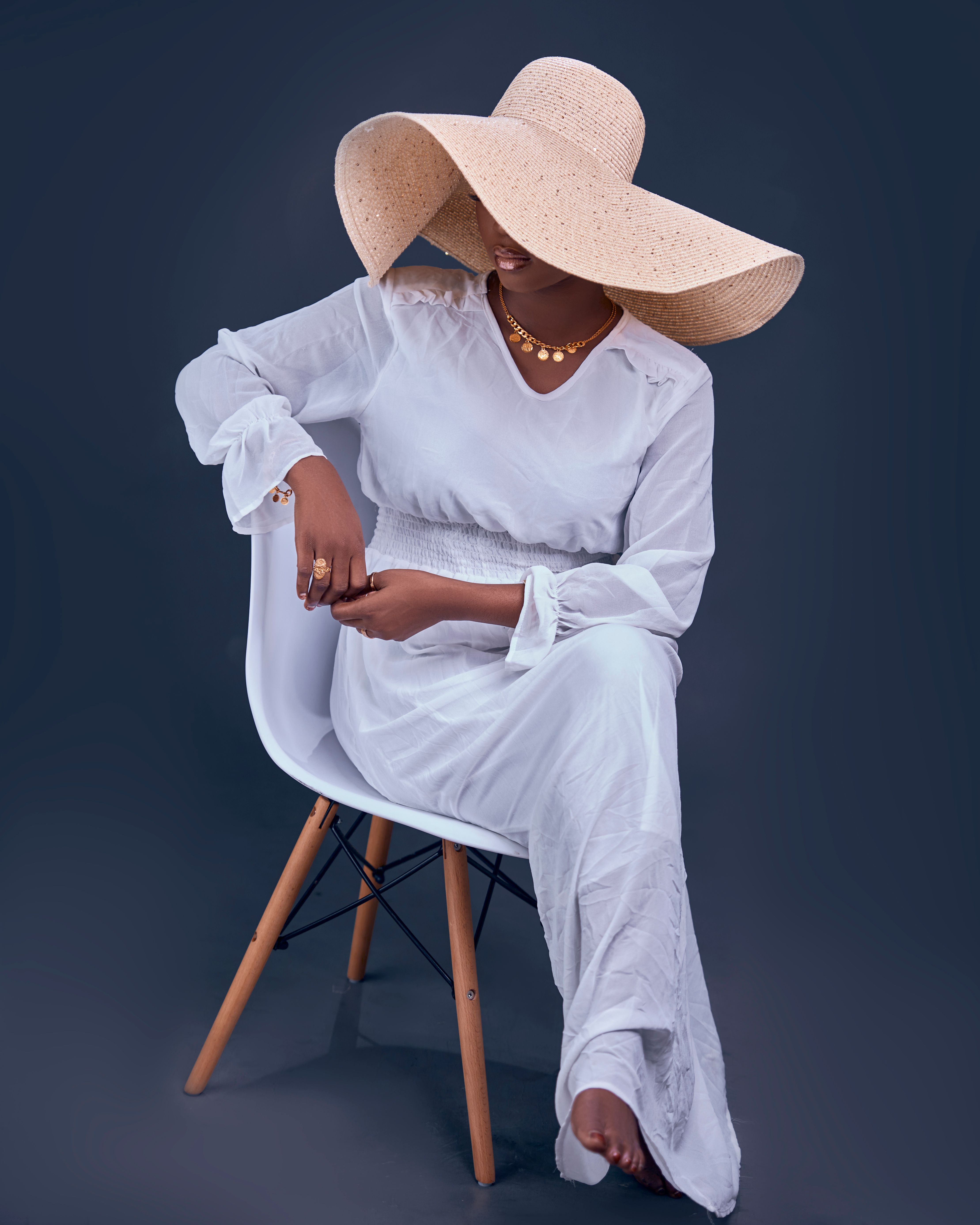 An elegant woman in a flowing white dress and a matching wide-brimmed hat, echoing the christening silhouette.