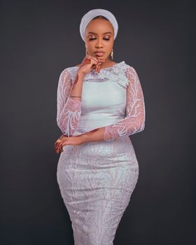 Elegant portrait of a woman in a stylish white lace dress with a thoughtful pose, embodying sophistication.