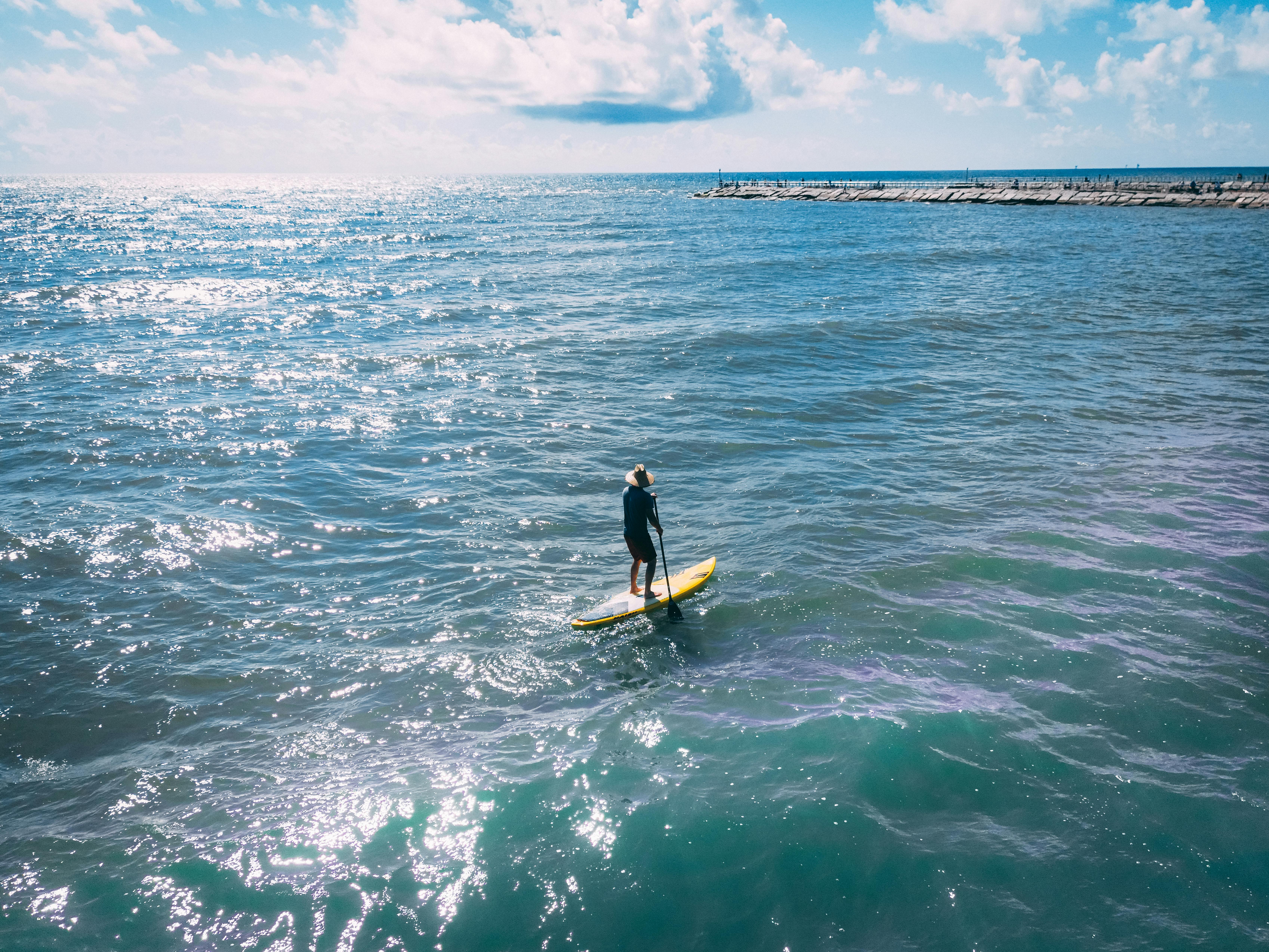A person paddleboarding solo on the ocean, enjoying a peaceful sunny day.