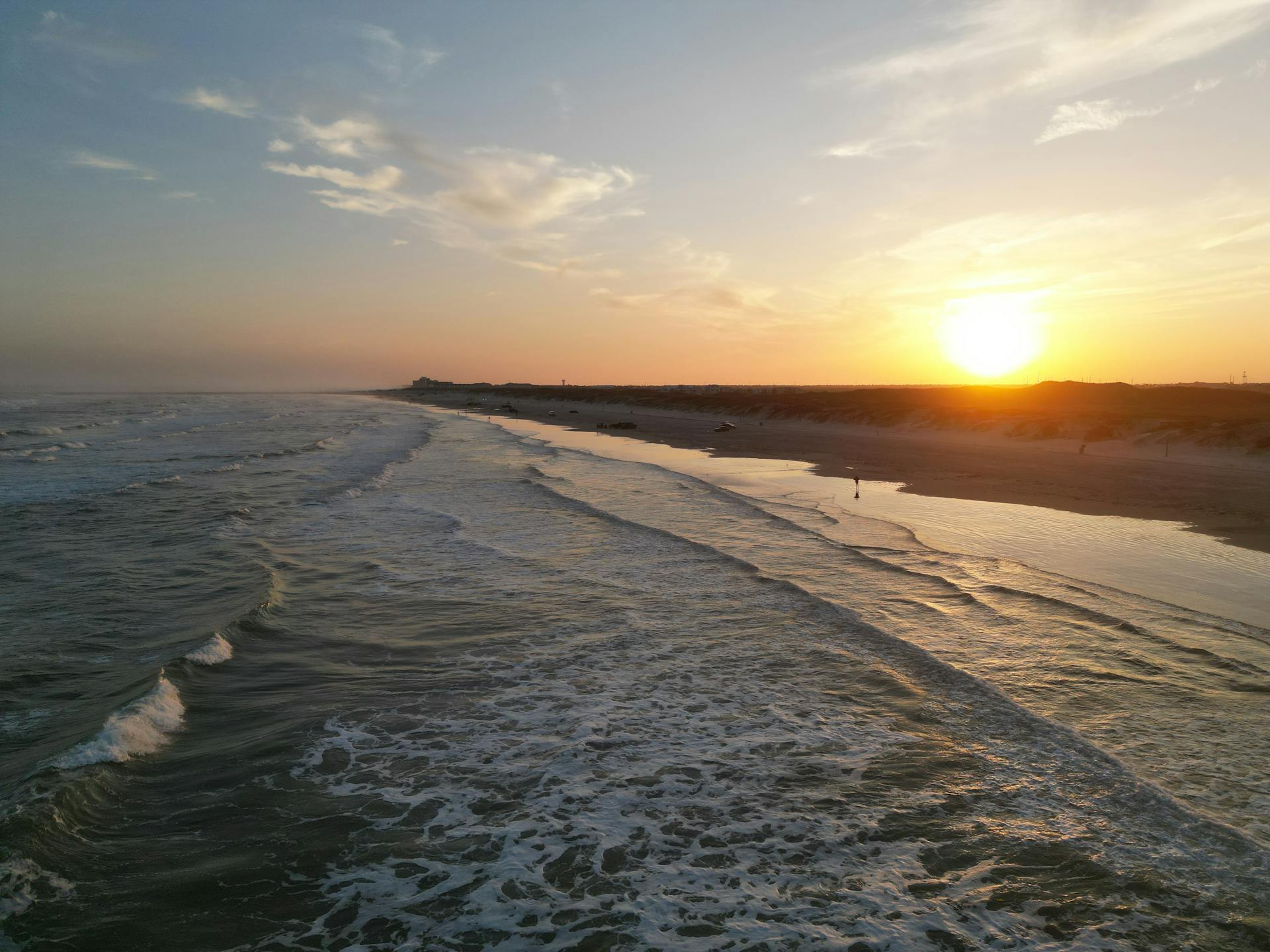 Breathtaking view of Corpus Christi beach at sunset, showcasing serene waves and glowing horizon.