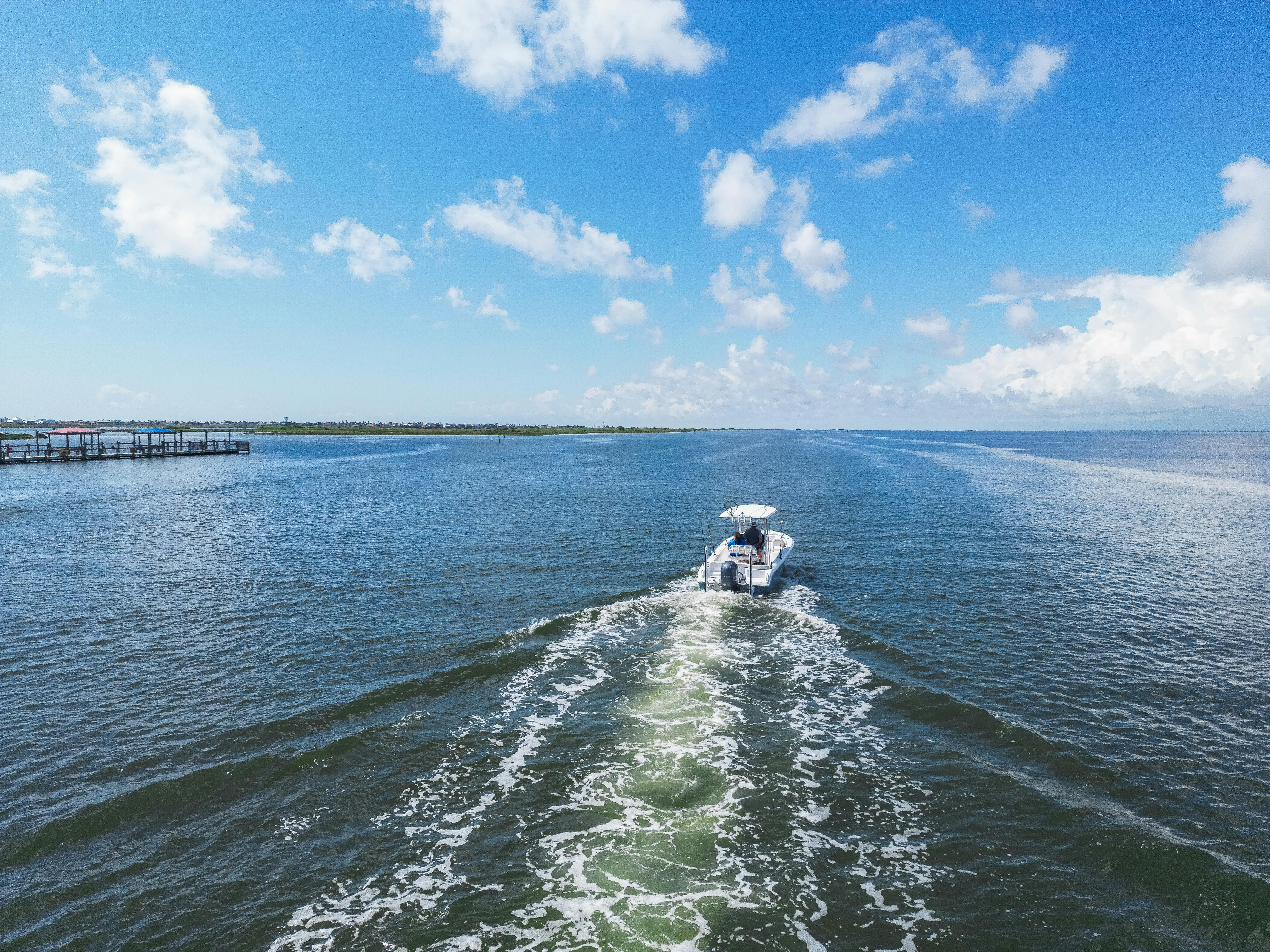 A boat cruises through Corpus Christi Bay under a bright summer sky, exuding freedom and adventure.