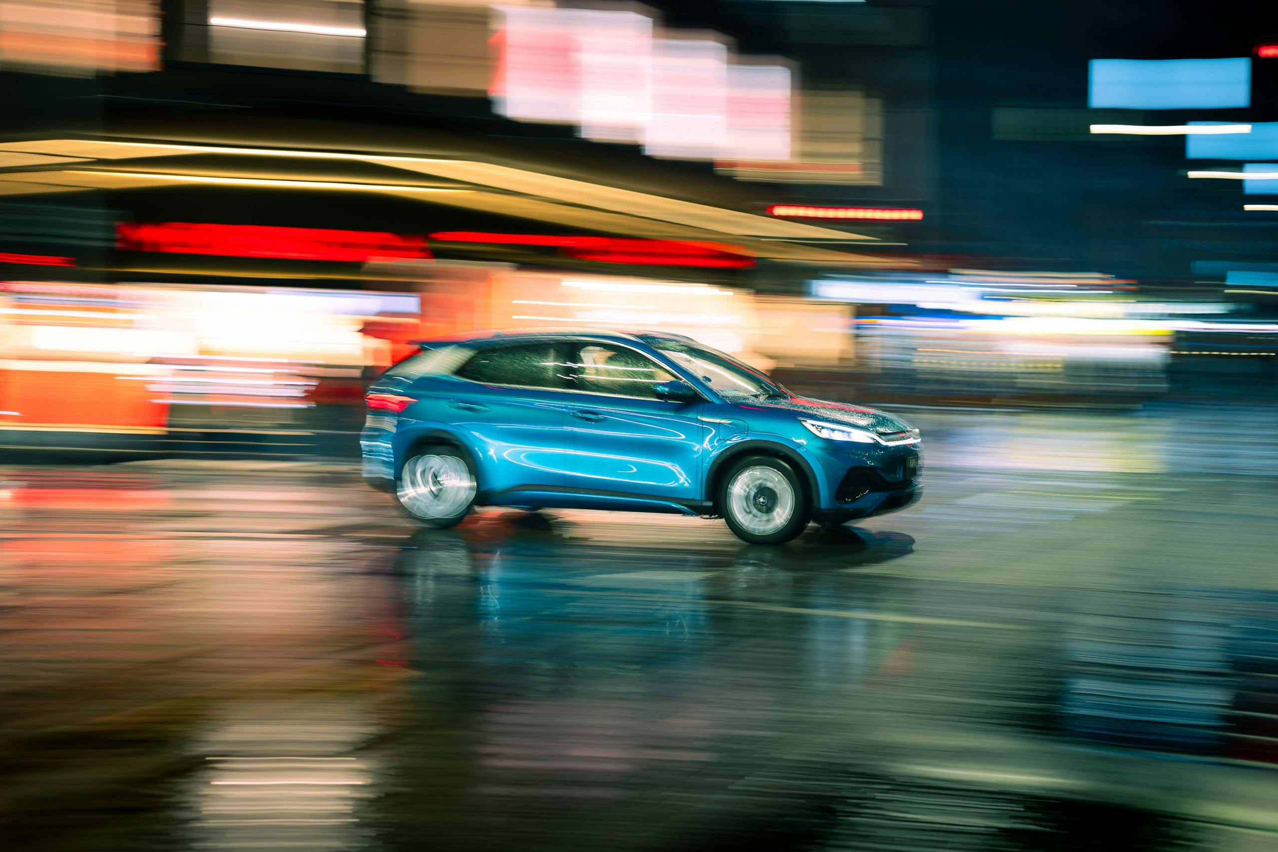 A vibrant night shot capturing a blue car in motion through Sydney's streets, highlighting light trails and urban energy.
