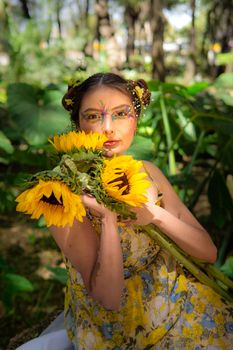 Woman with colorful makeup and sunflowers in a lush outdoor setting in Mexico City.