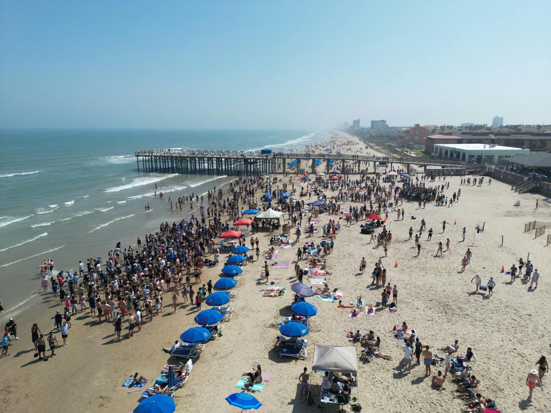 Lively beach scene at South Padre Island, Texas with crowds enjoying the sunny day.