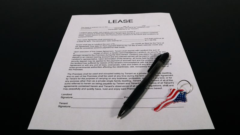 renter reading a lease agreement at a kitchen table with a laptop