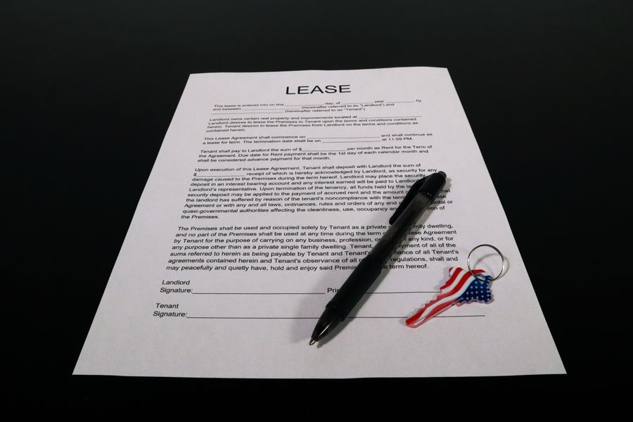 A lease agreement document with a pen and a house-key keychain on a table