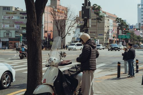 Free Urban street view in Seoul with people and scooter, showcasing local architecture and daily life. Stock Photo