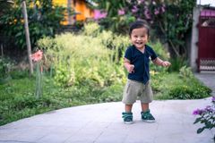 Happy toddler taking steps outdoors in a vibrant garden setting.