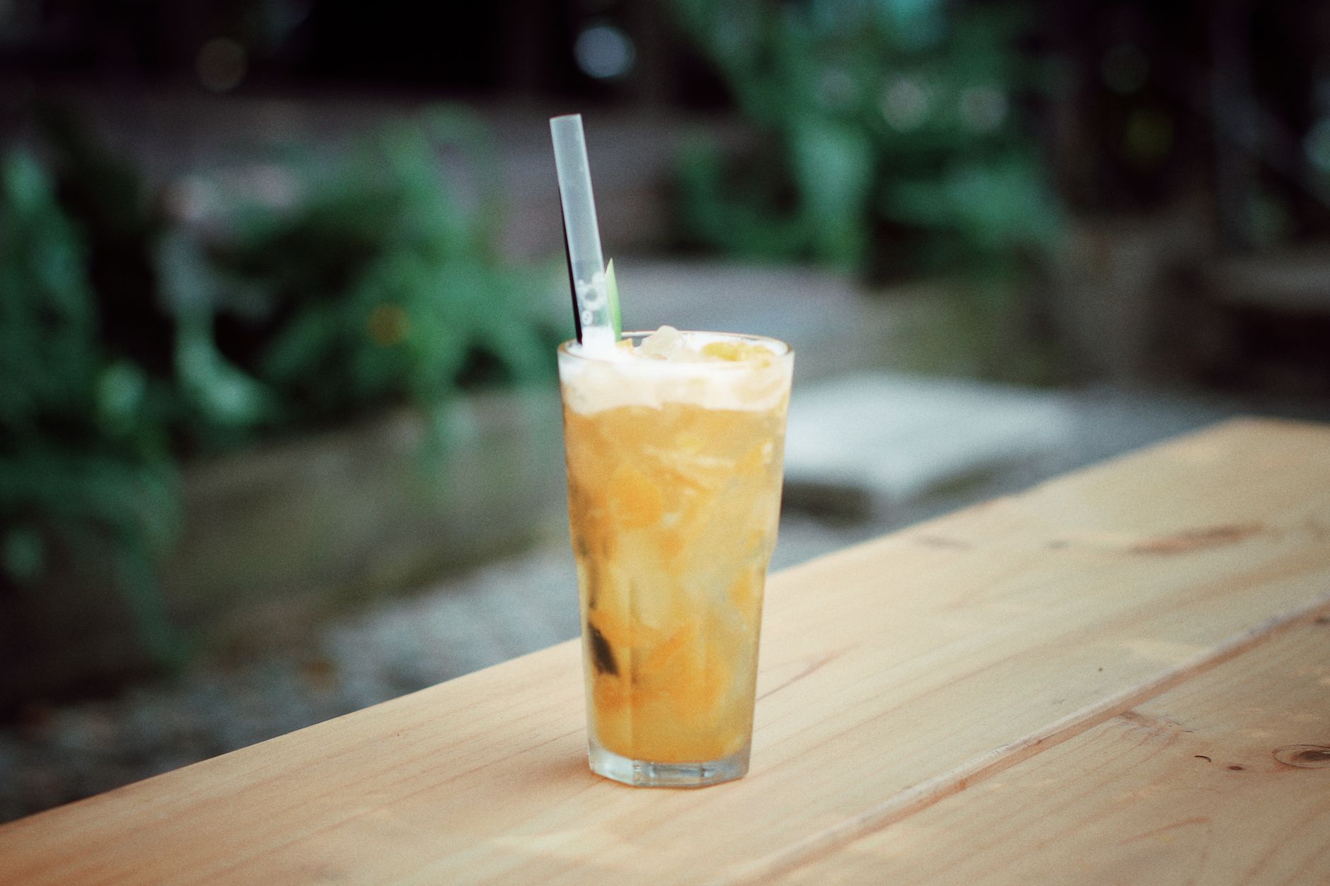 iced shake method for long covid fatigue — Chilled iced orange drink with straw on an outdoor wooden table. Refreshing and vibrant.