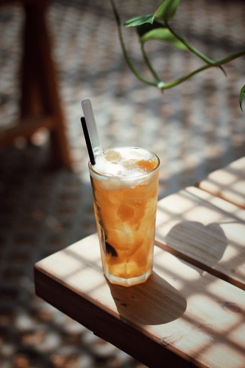 Free Glass of iced tea on a sunny wooden table with natural shadows Stock Photo