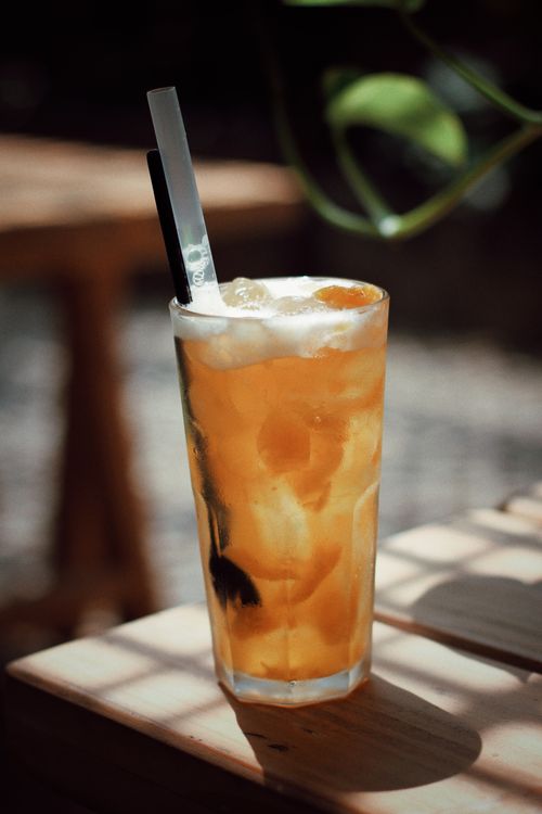 Free A tall glass of iced tea with ice and a straw basking in warm sunlight. Stock Photo