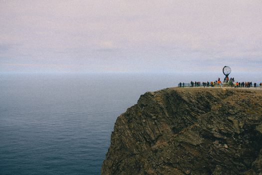 Breathtaking view of the Nordkapp cliff in Finnmark, Norway with tourists enjoying the panorama.