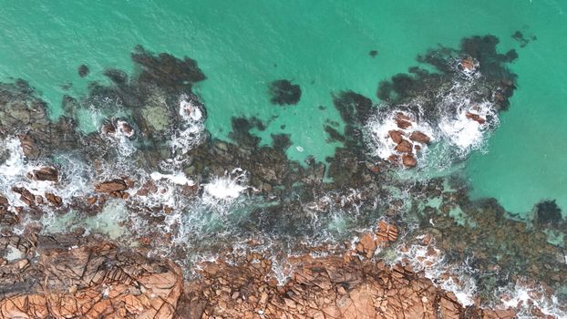 Stunning aerial shot of rugged Busselton coastline with turquoise waves crashing on rocks.