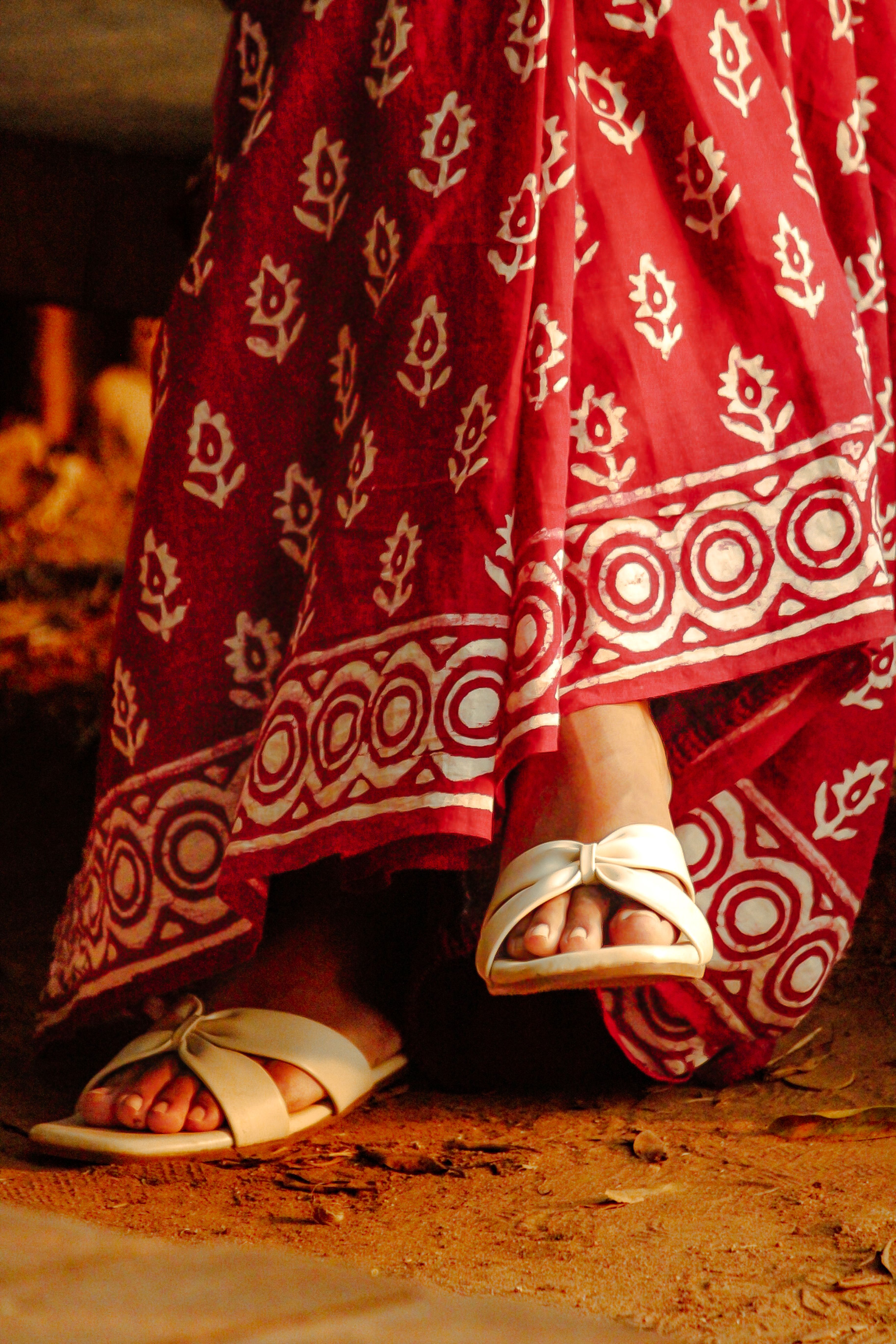 Close-up of red saree with white sandals in Kozhikode, Kerala highlighting traditional fashion.