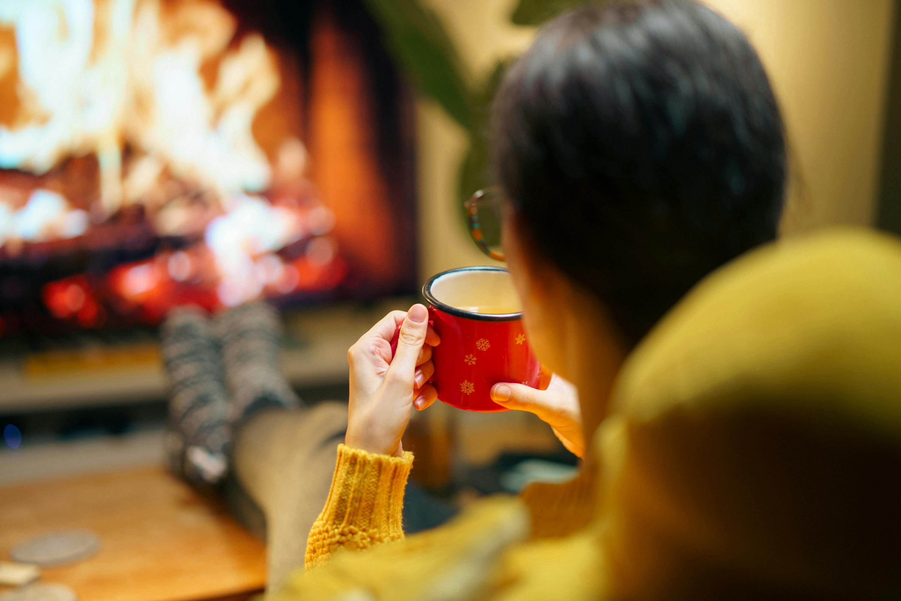 Cozy living room with a fireplace, blanket, and hot cocoa on a snowy day - Heating Repair Bethel Park PA
