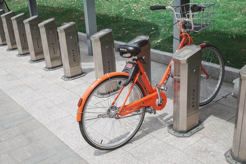 Red rental bike parked in a Japanese station with green background and text on stands.