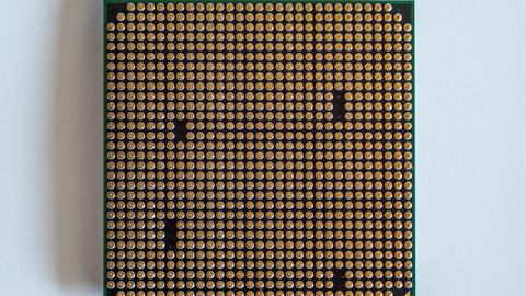 Detailed view of a computer processor, showcasing its pins, against a clean white backdrop.