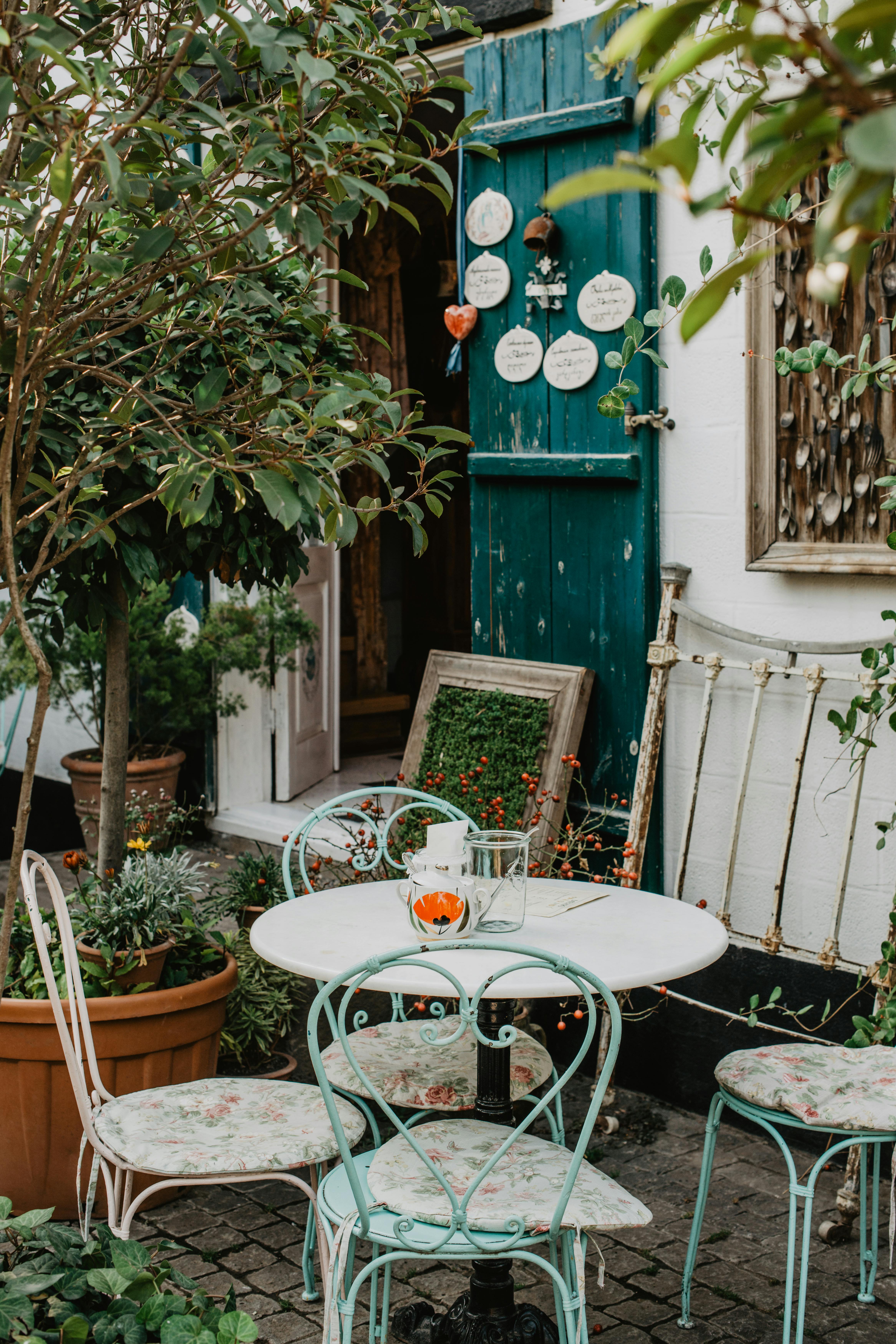 Charming outdoor café setting with vintage furniture and lush greenery.