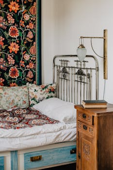 Cozy vintage bedroom featuring floral decor, antique iron bedframe, and wooden nightstand.