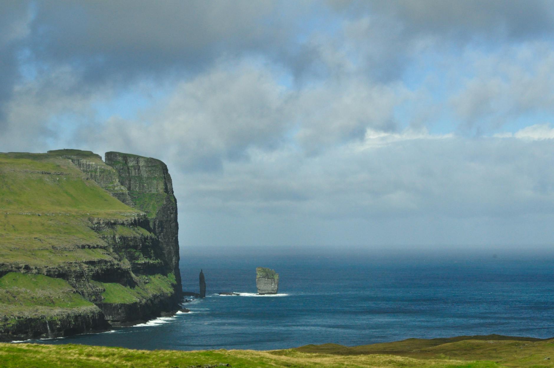 Wanderlust On A Shoestring: 5 Tips For Finding Unbeatable Travel Discounts 1 majestic cliffs and sea stacks on the faroe islands under a cloudy sky, showcasing nature's grandeur.