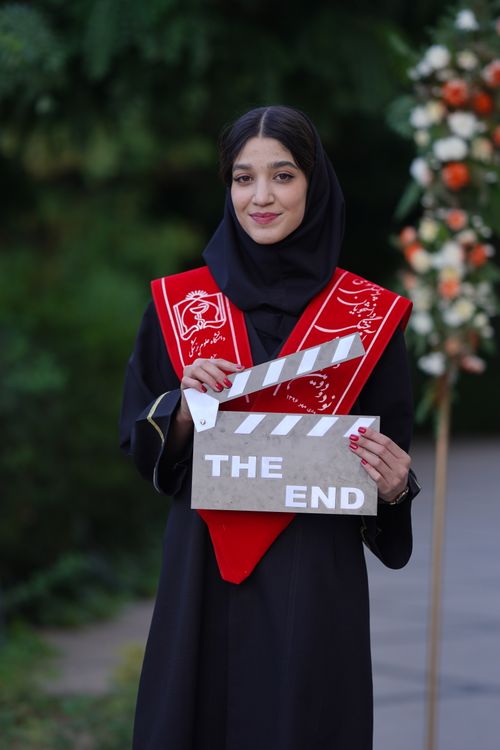 Free A young woman in graduation attire holding a clapboard saying 'The End'. Stock Photo