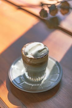 A deliciously creamy coffee served on a sunlit table, perfect for coffee lovers.