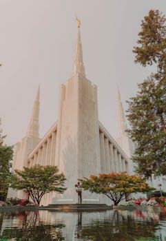 Capture of the stunning Portland Oregon Temple surrounded by lush greenery and reflective pool.