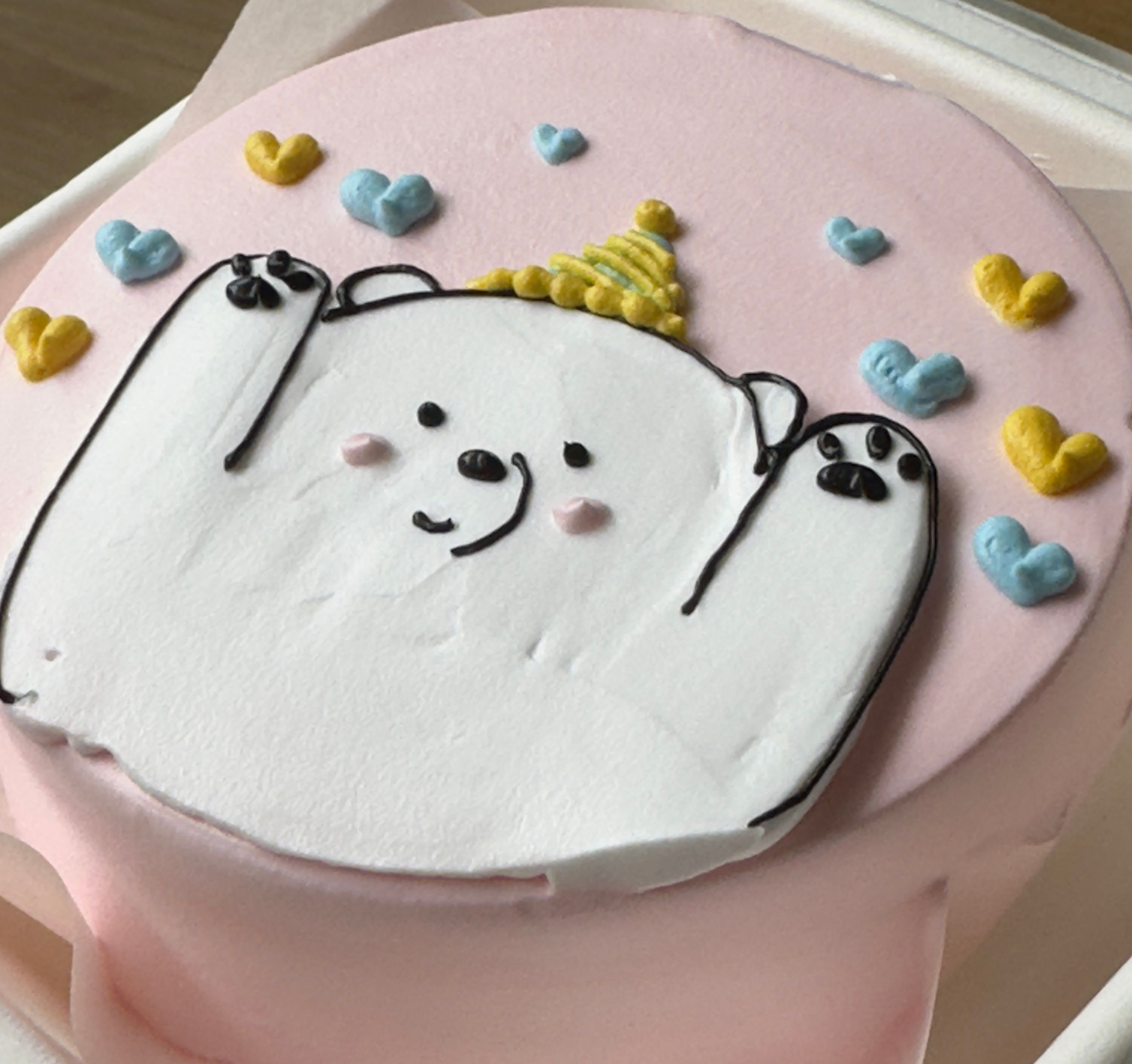 Charming bear-themed cake with colorful heart decorations. Perfect for a birthday celebration.