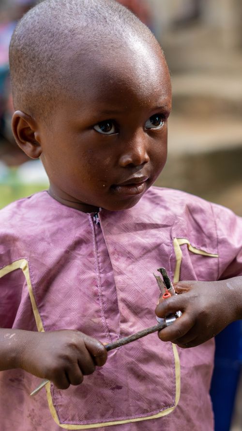 Free A young child with an innocent expression holding a tool, photographed in natural light outdoors. Stock Photo