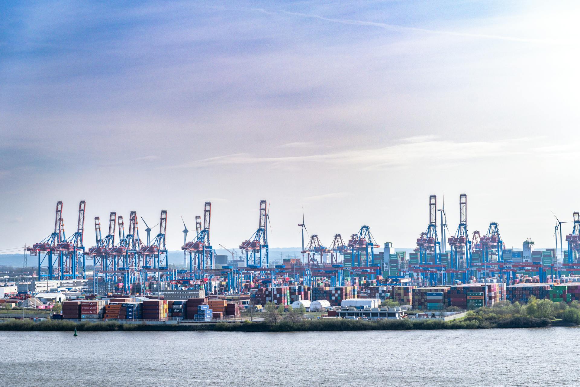 A vibrant view of Hamburg's container port with cranes and shipping containers under clear skies.