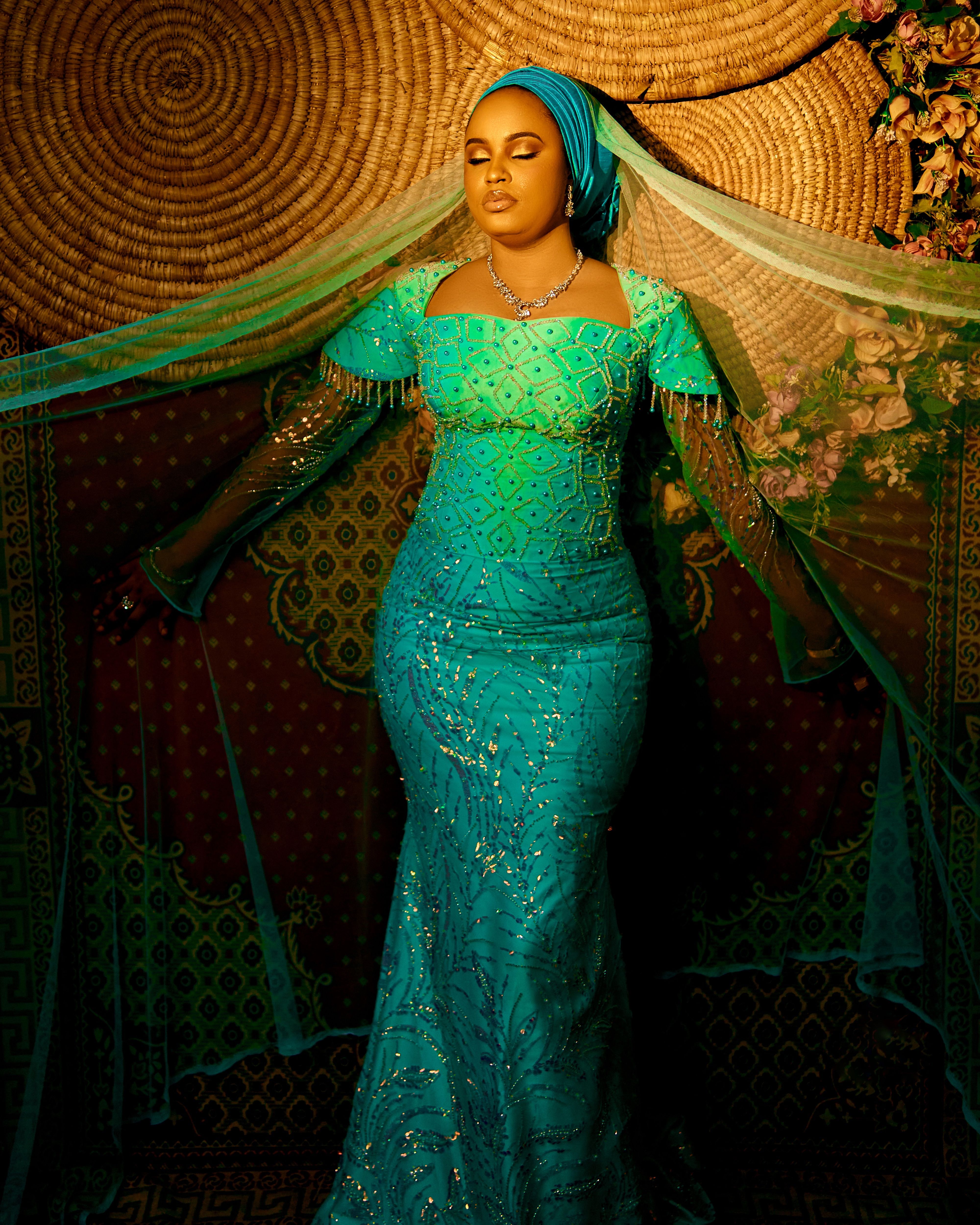 Woman in a beautifully embroidered turquoise dress with intricate designs.