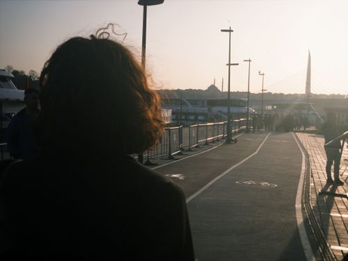 Free A person walks on an urban path at sunset, with a bridge and city skyline visible. Stock Photo