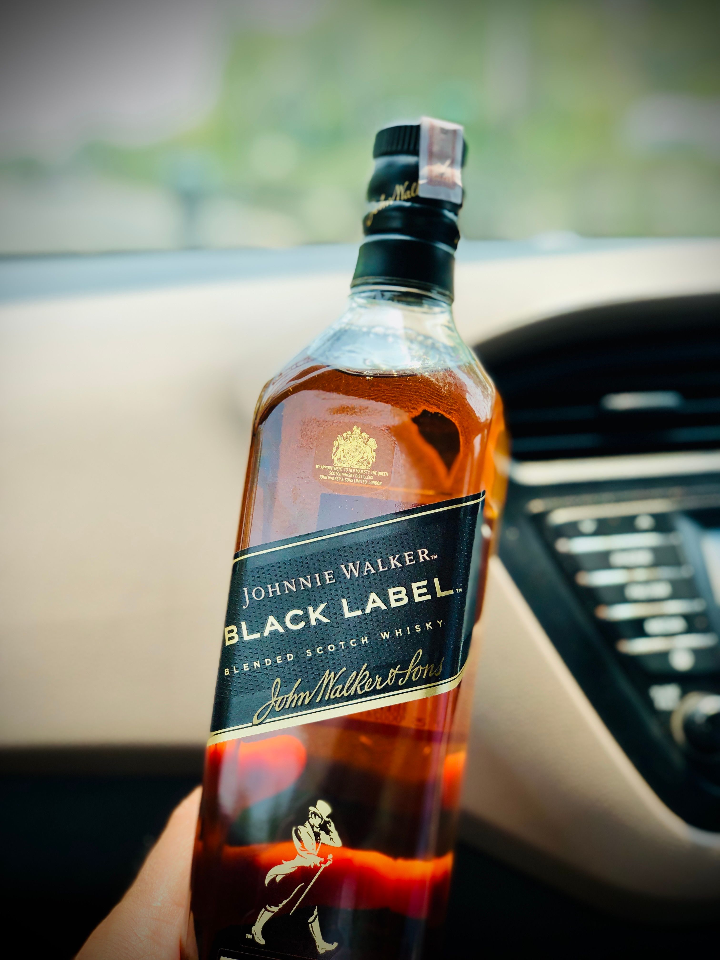 Elegant Johnnie Walker Black Label whisky bottle set in car interior.