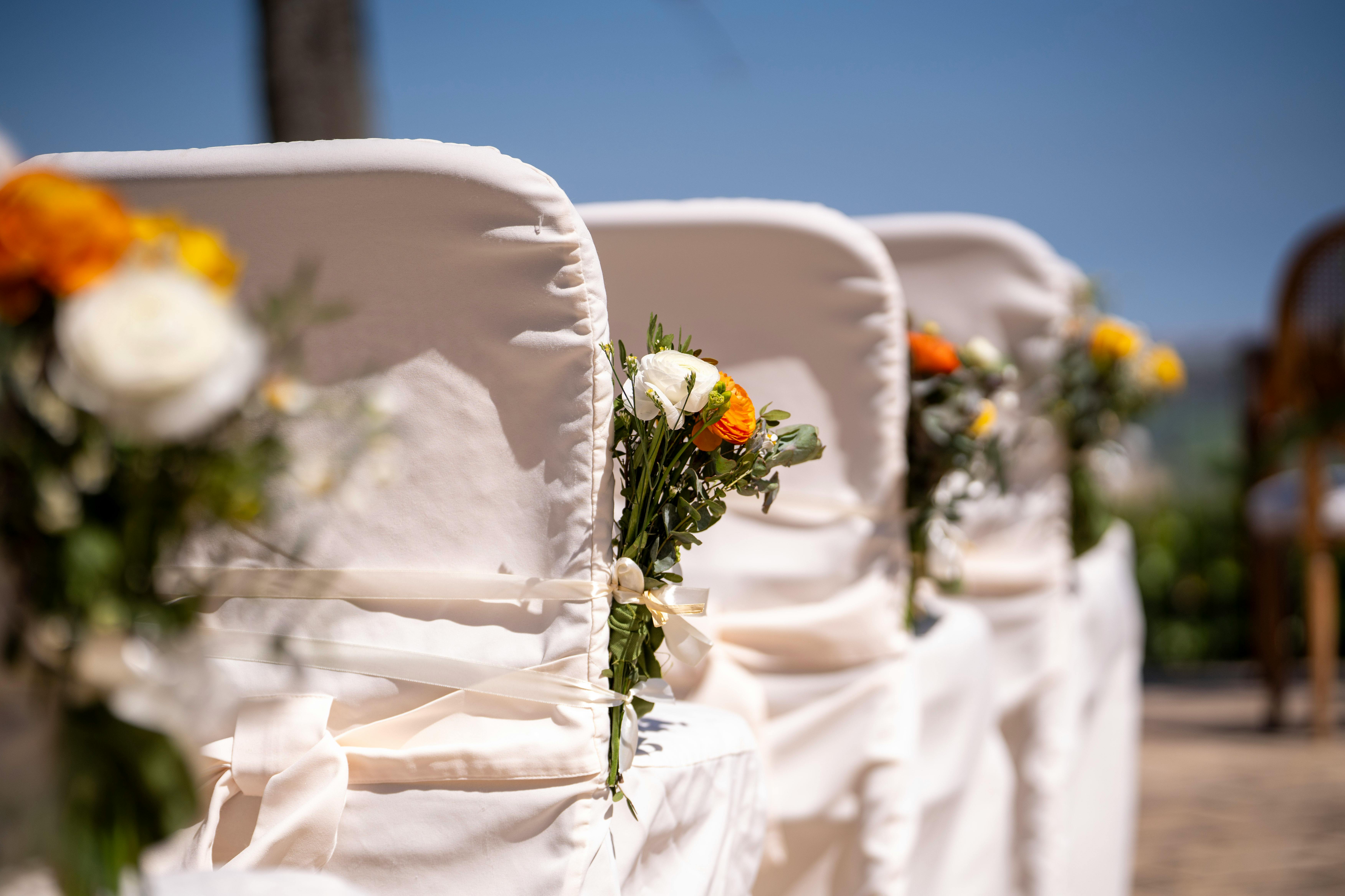 Chairs arranged outdoors with floral decorations for a wedding ceremony.