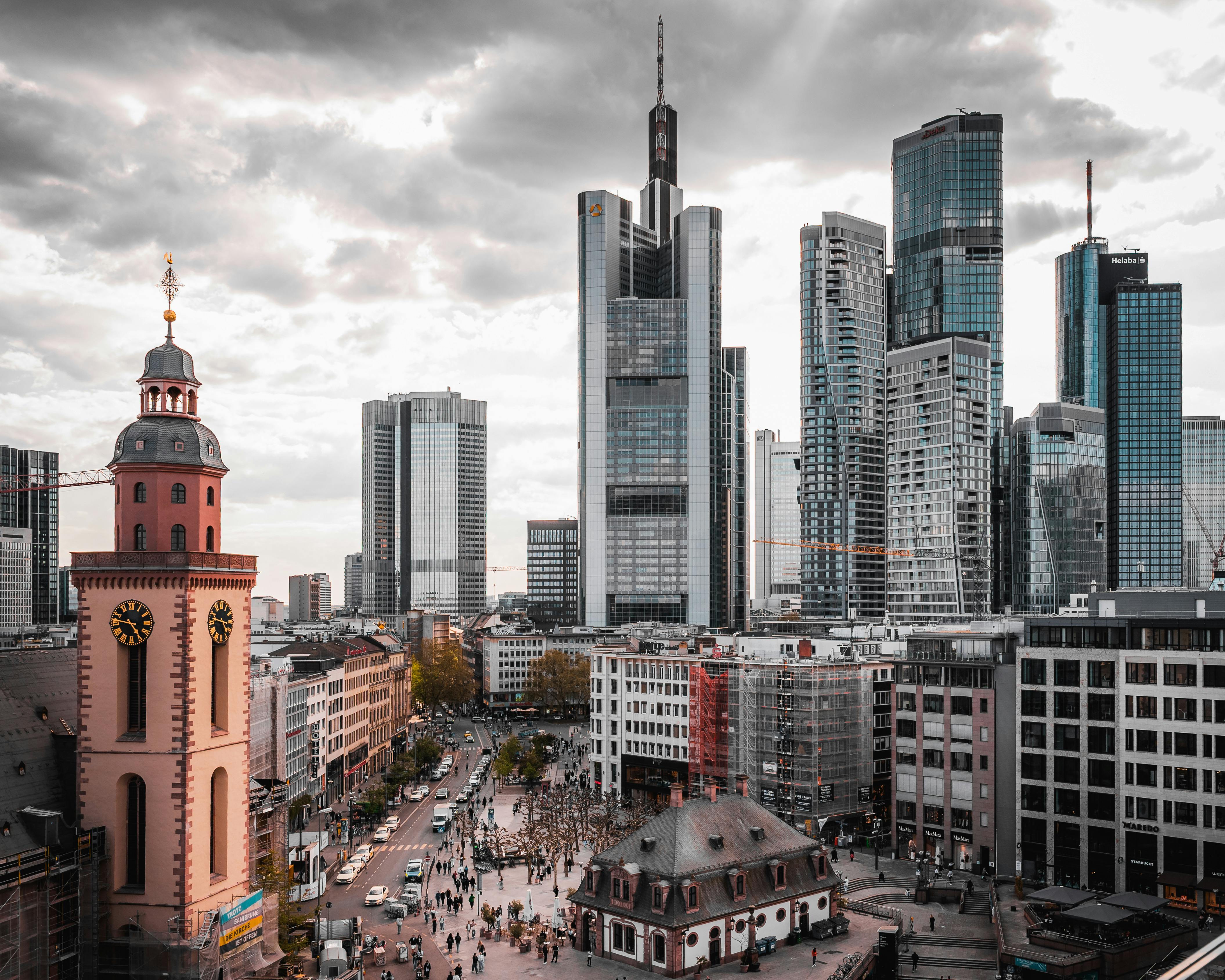 A stunning view of Frankfurt's skyscrapers and historical church under a cloudy sky.