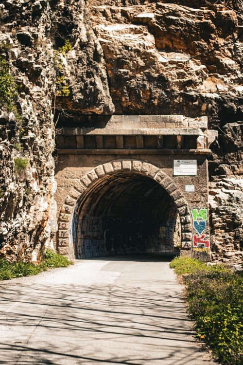 Free Explore this ancient stone tunnel carved into the rocky cliffside, surrounded by nature. Stock Photo
